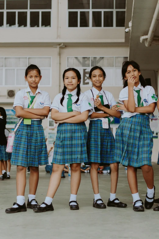 three school girls in kilts stand with their arms crossed