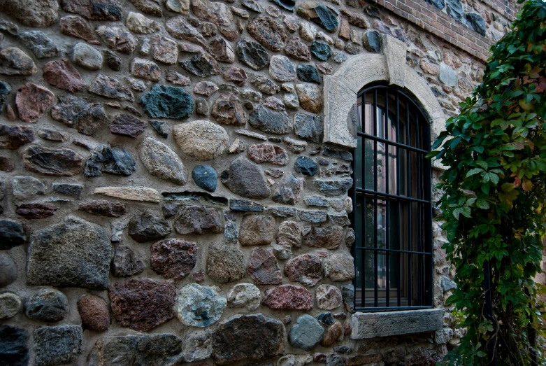 a wall made of rocks is surrounded by a fence