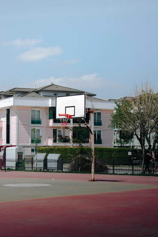 the basketball goal is on the post in front of a building