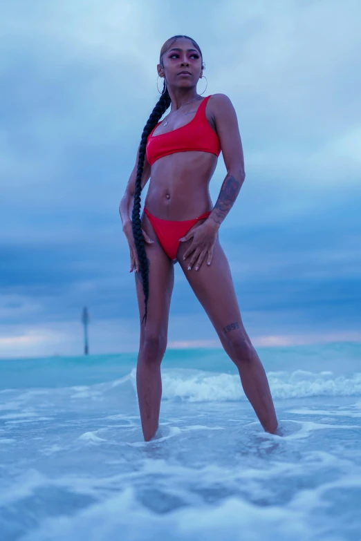 a woman wearing a red bikini and holding long hair standing in the water