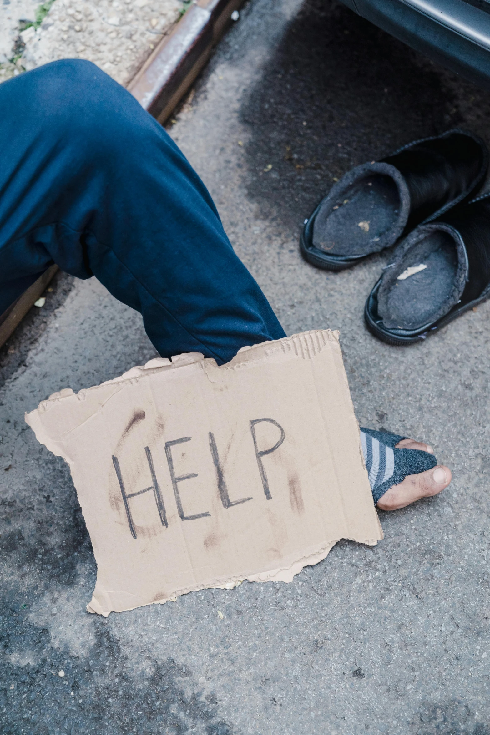 someone sitting on the ground holding a sign with help