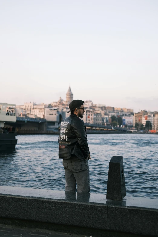 a man standing on a riverbank while looking at the city