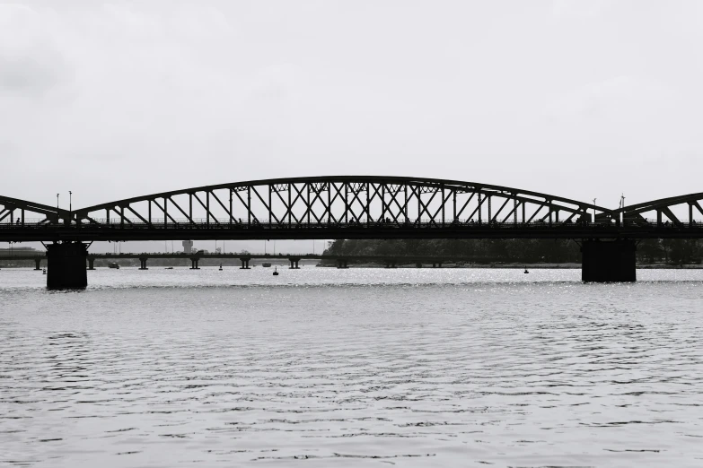 an iron bridge crosses across the water in a black and white po