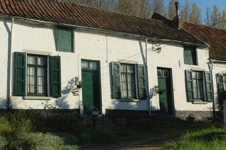 an old white building with three green doors and windows
