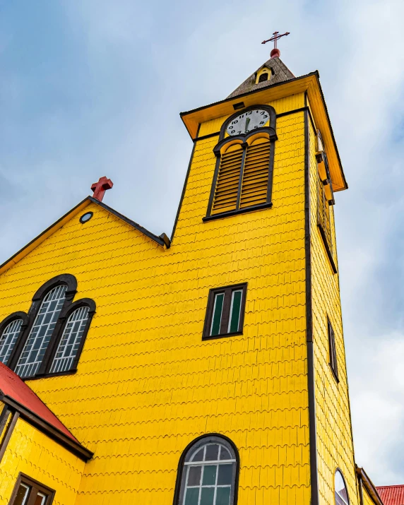 a tall yellow building with arched windows and a clock on the side