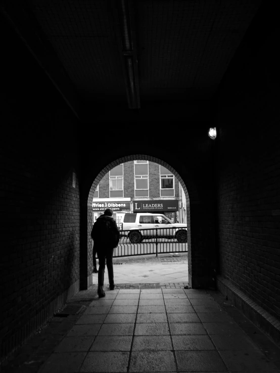 a person walks in an archway by a fence