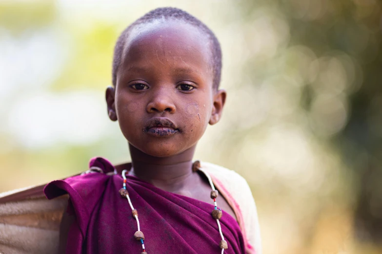 a small african child wears a necklace of beads