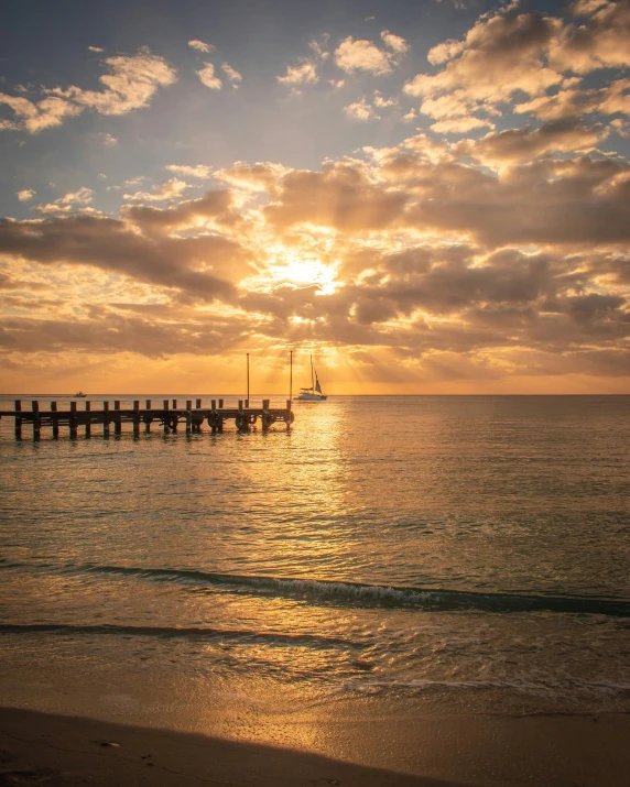 the pier and the sea during sunrise with clouds in background