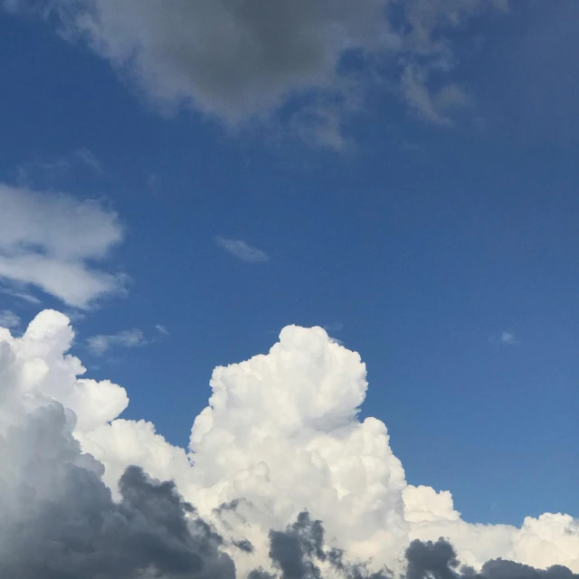 an airplane flying through a blue sky with fluffy white clouds