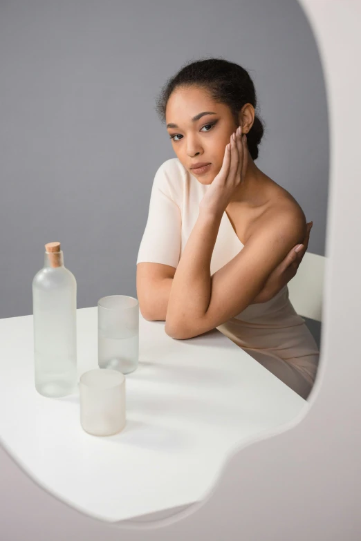 there is a woman sitting at the table with an empty bottle