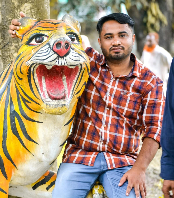 a man poses next to a statue of a tiger