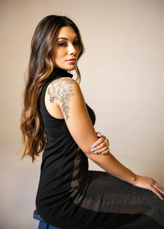 a girl sitting on top of a stool with her arm resting on the edge