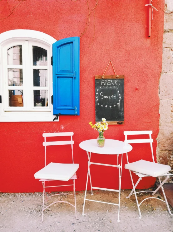 a red wall with two chairs and a table