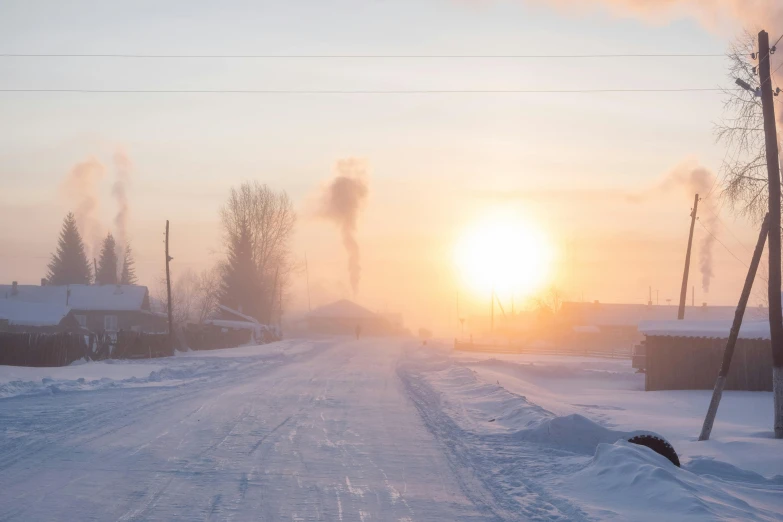 the sun rising over a street with a snow covered sidewalk