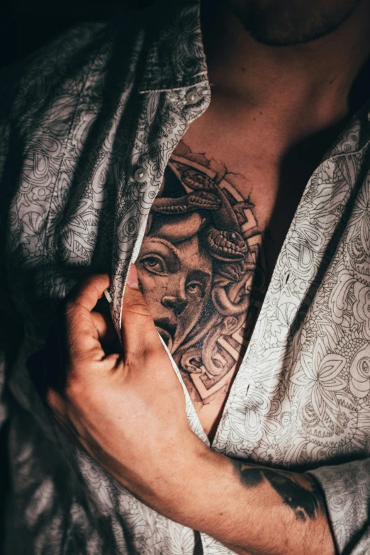 a person holding their shirt off and wearing a tattoo