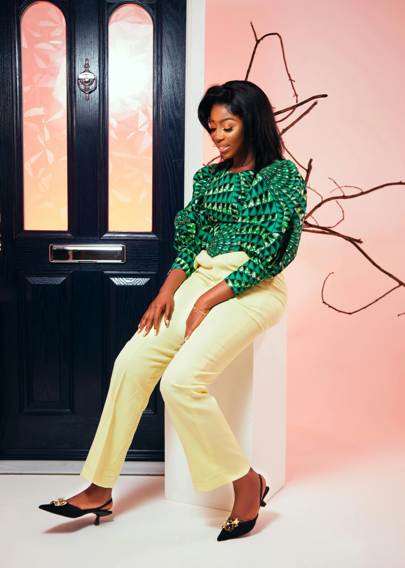 an attractive lady sitting on the ledge wearing yellow pants