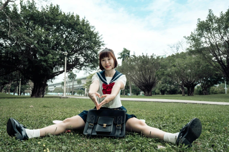  sitting in grass on her knees, holding purse