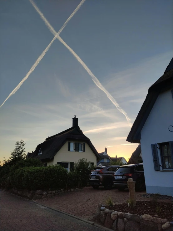 two planes streak through the sky over a house