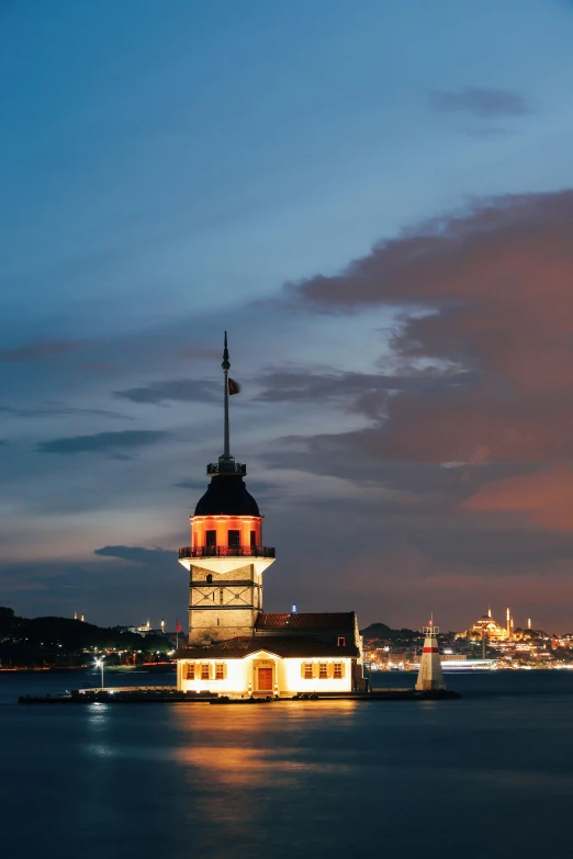 this is a lighthouse in the water with the city lights in the background