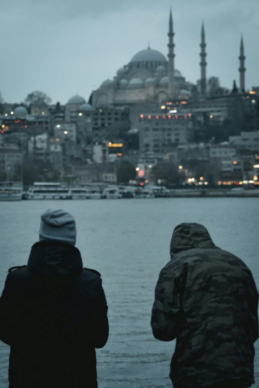 two people looking over water toward buildings in the background