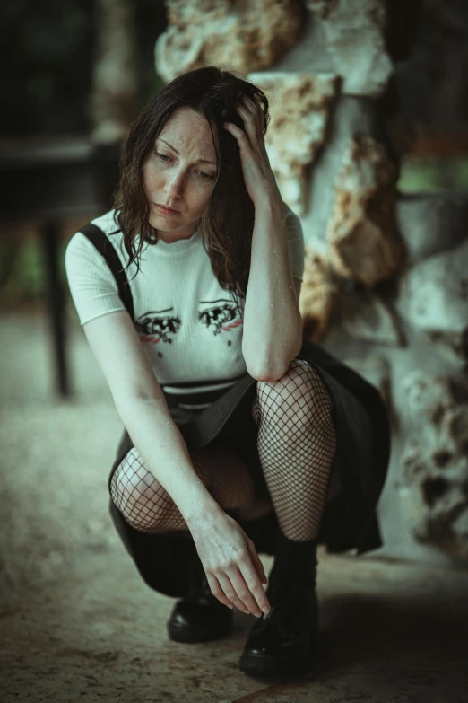 a woman wearing fishnet stockings and boots is leaning against a wall