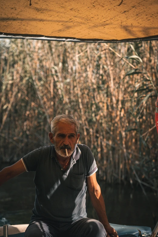 a man on a boat with reeds in the water behind him