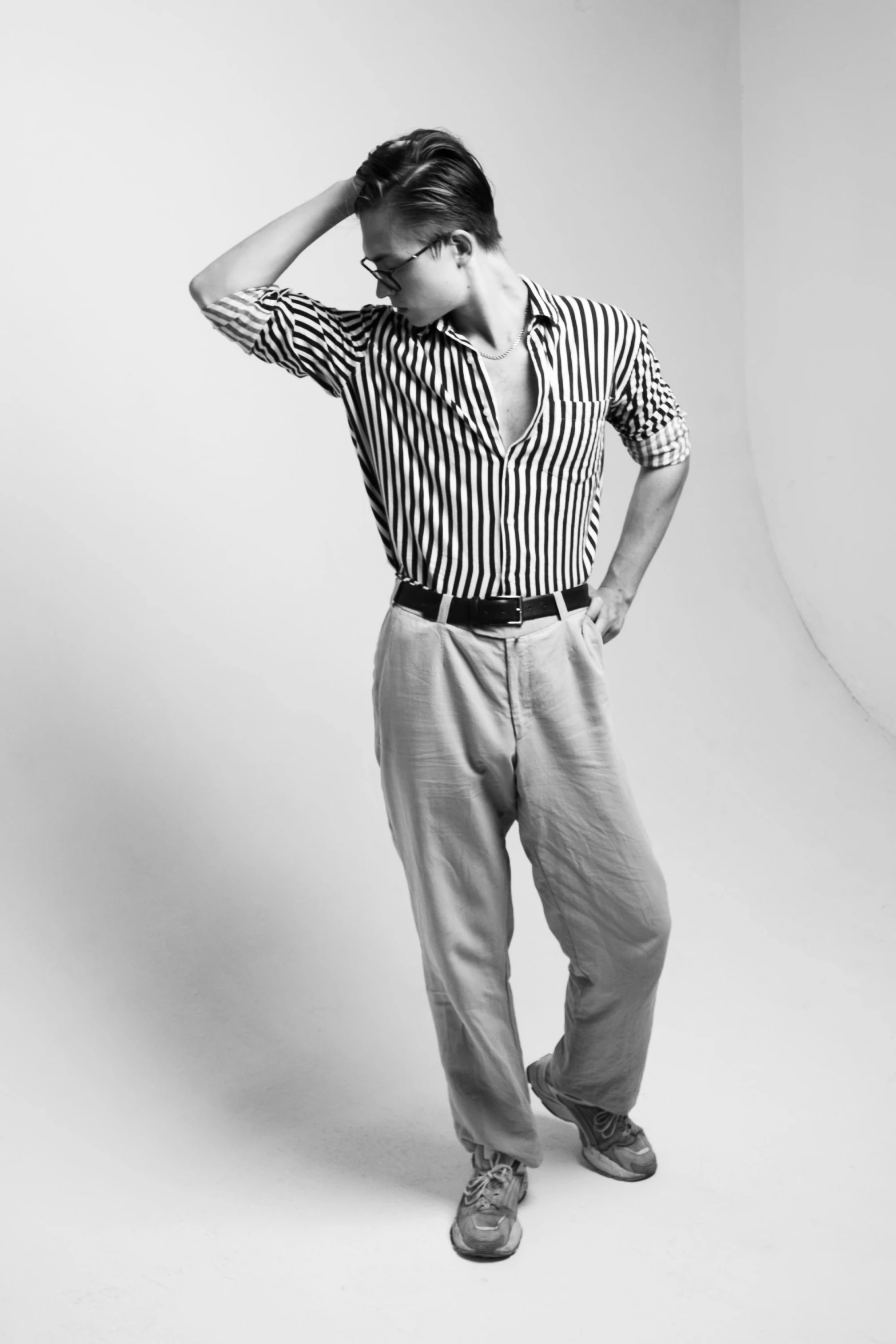 a man wearing striped shirt and pants standing up against a wall