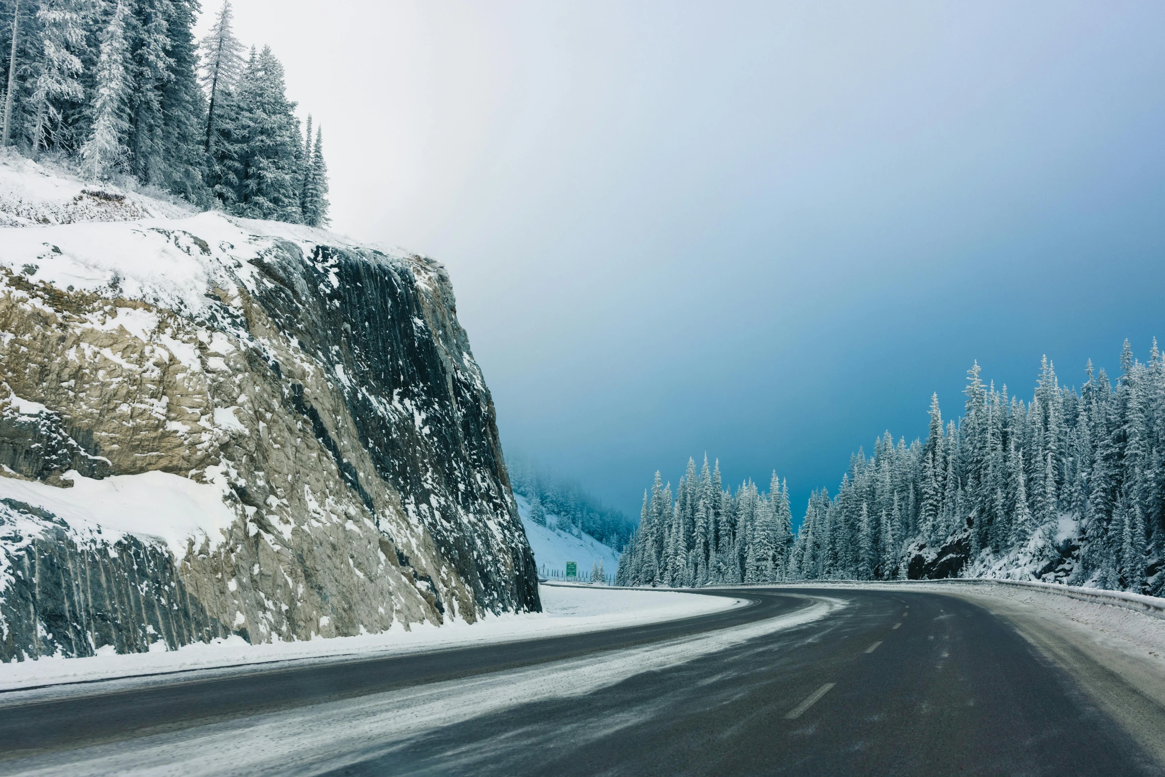 the snow covered side of a mountain near a road