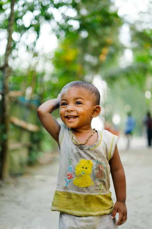 a little boy with the hat on, laughing and holding his hand behind his head