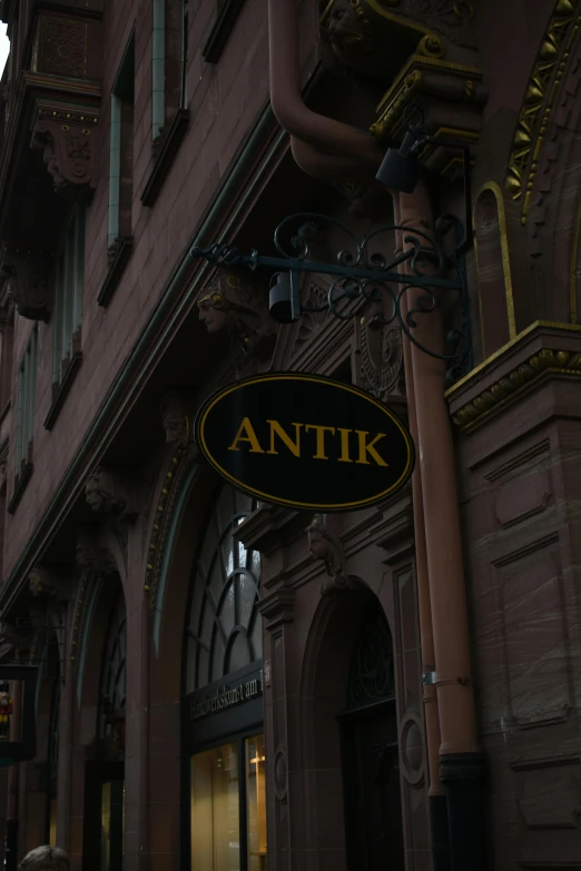 an entrance sign to a building with people walking under it