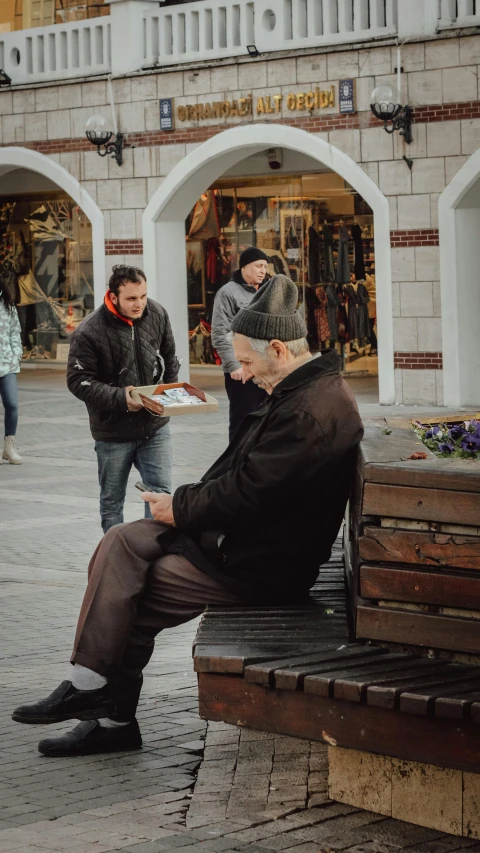 two men are sitting on a bench outside