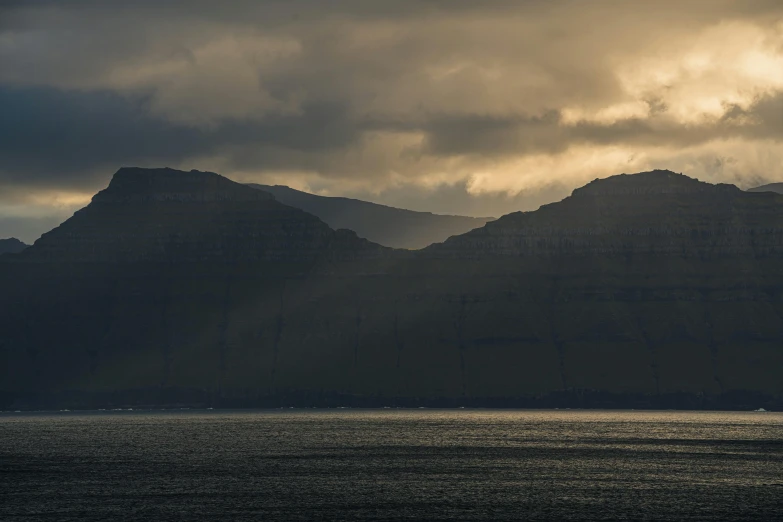 dark clouds are hovering over mountains and body of water