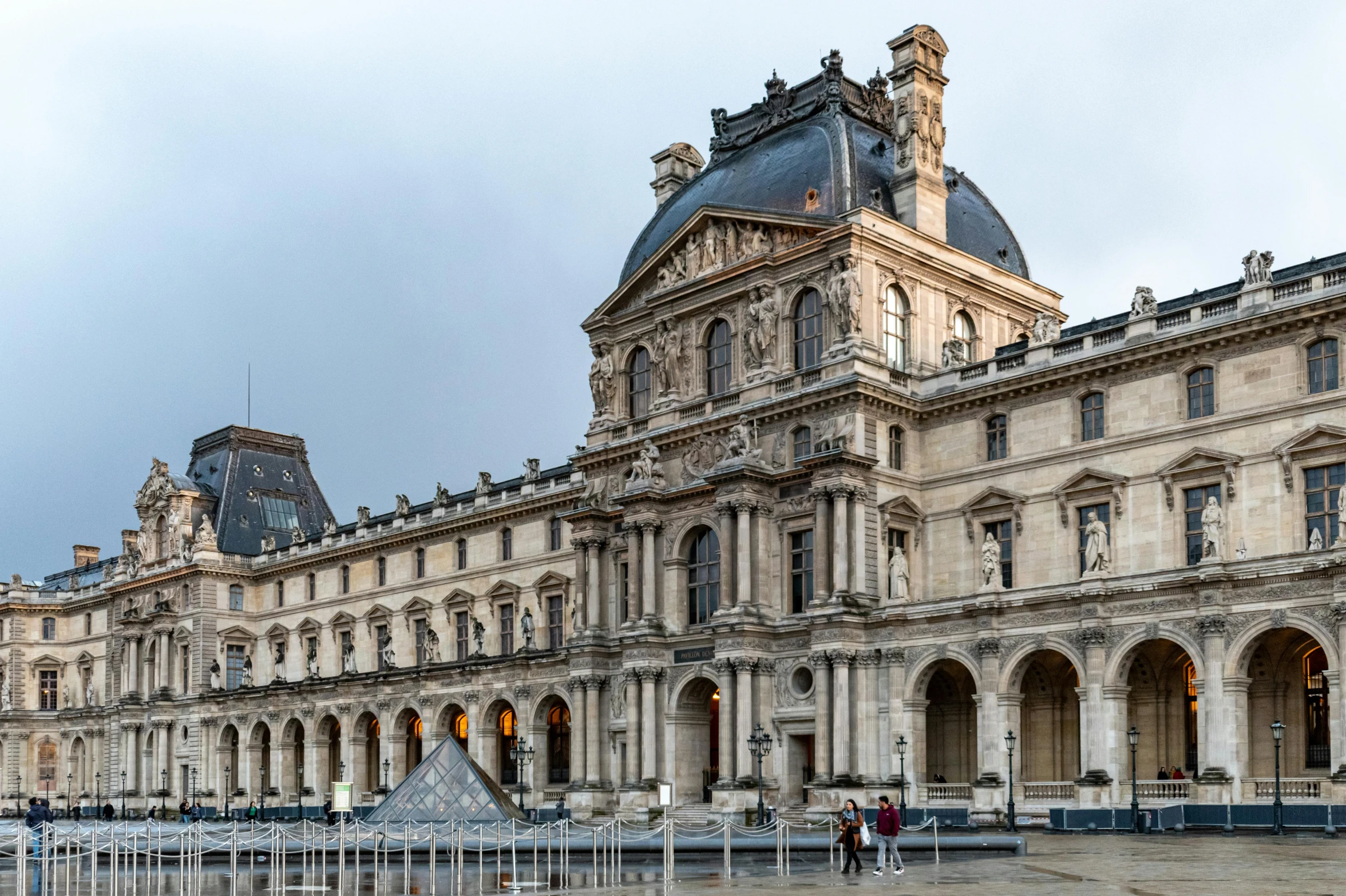 an old building with statues and a pyramid in front of it