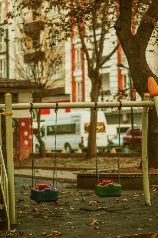 the city street has a tree and several children's swings