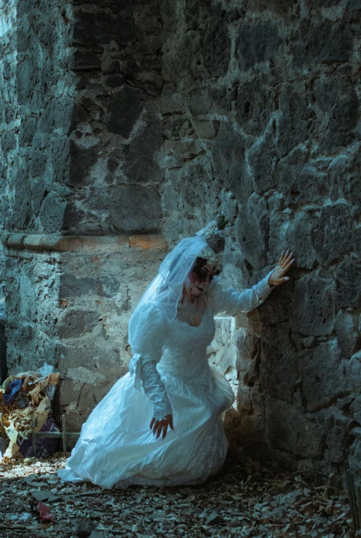 the bride leans against a stone wall posing for a po