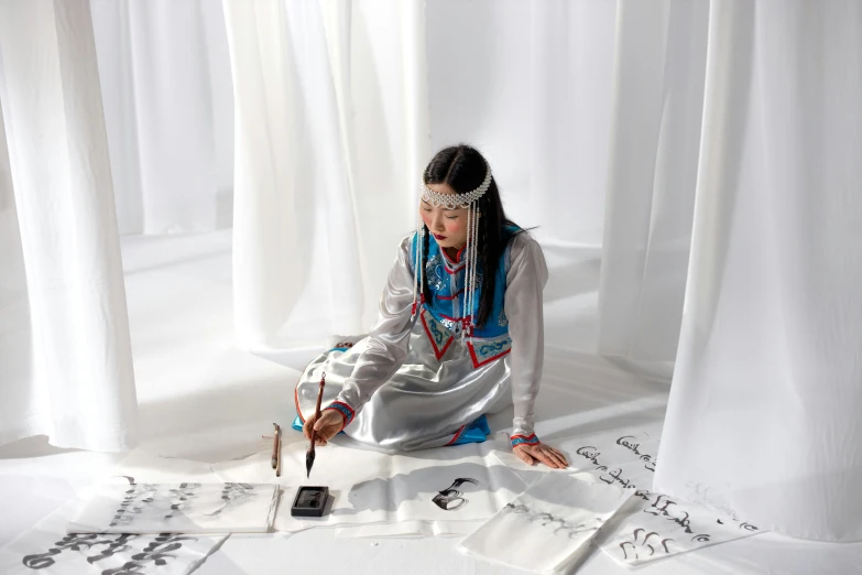 a woman with a feather and a flower is sitting on the ground next to some drawings