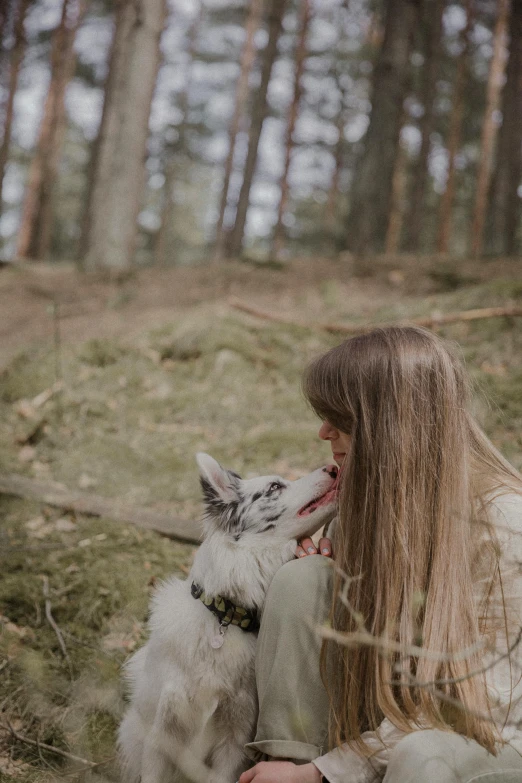 a woman kissing her dog in the woods