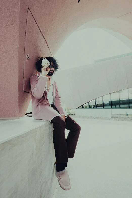 a man wearing glasses is sitting against a wall