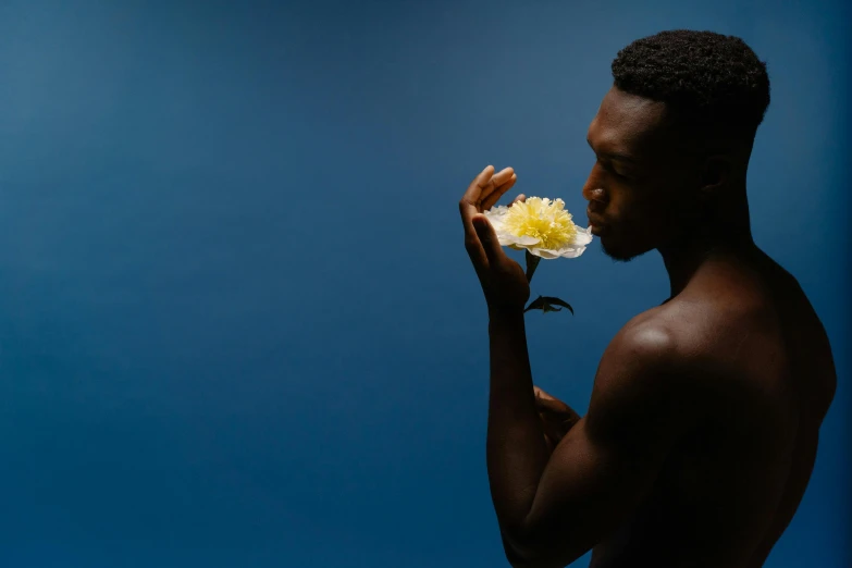 a man holds up a flower to the camera