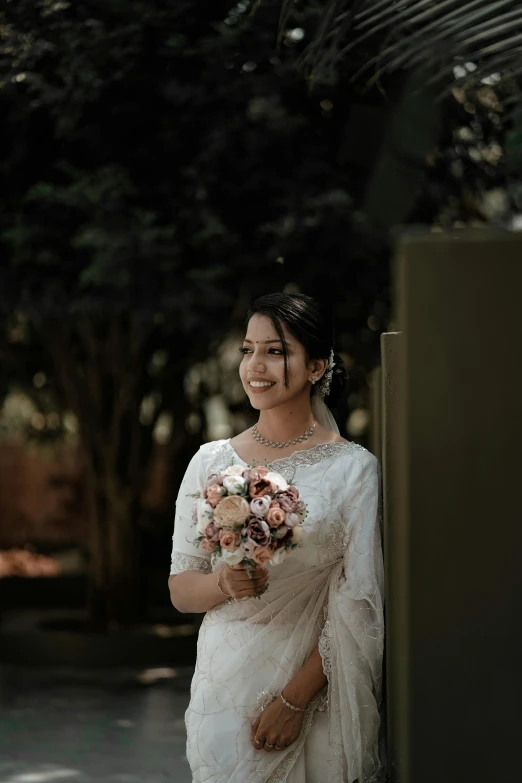 a smiling woman stands in front of some trees