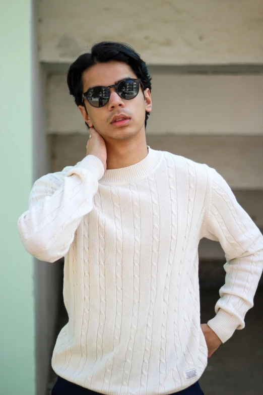 a man with sunglasses on posing in a white sweater