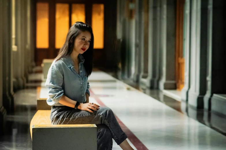 a woman in jeans sits on a wooden bench