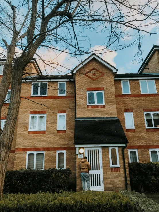 an apartment complex with large front gardens in the foreground and bare trees