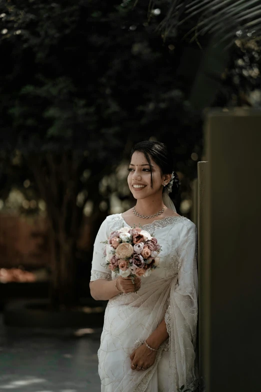 an asian bride stands in front of the tree