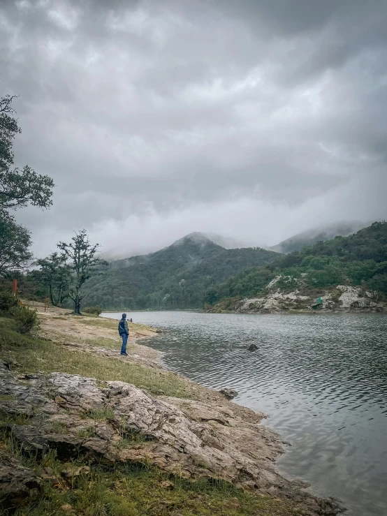 a person standing on the side of a hill near a body of water