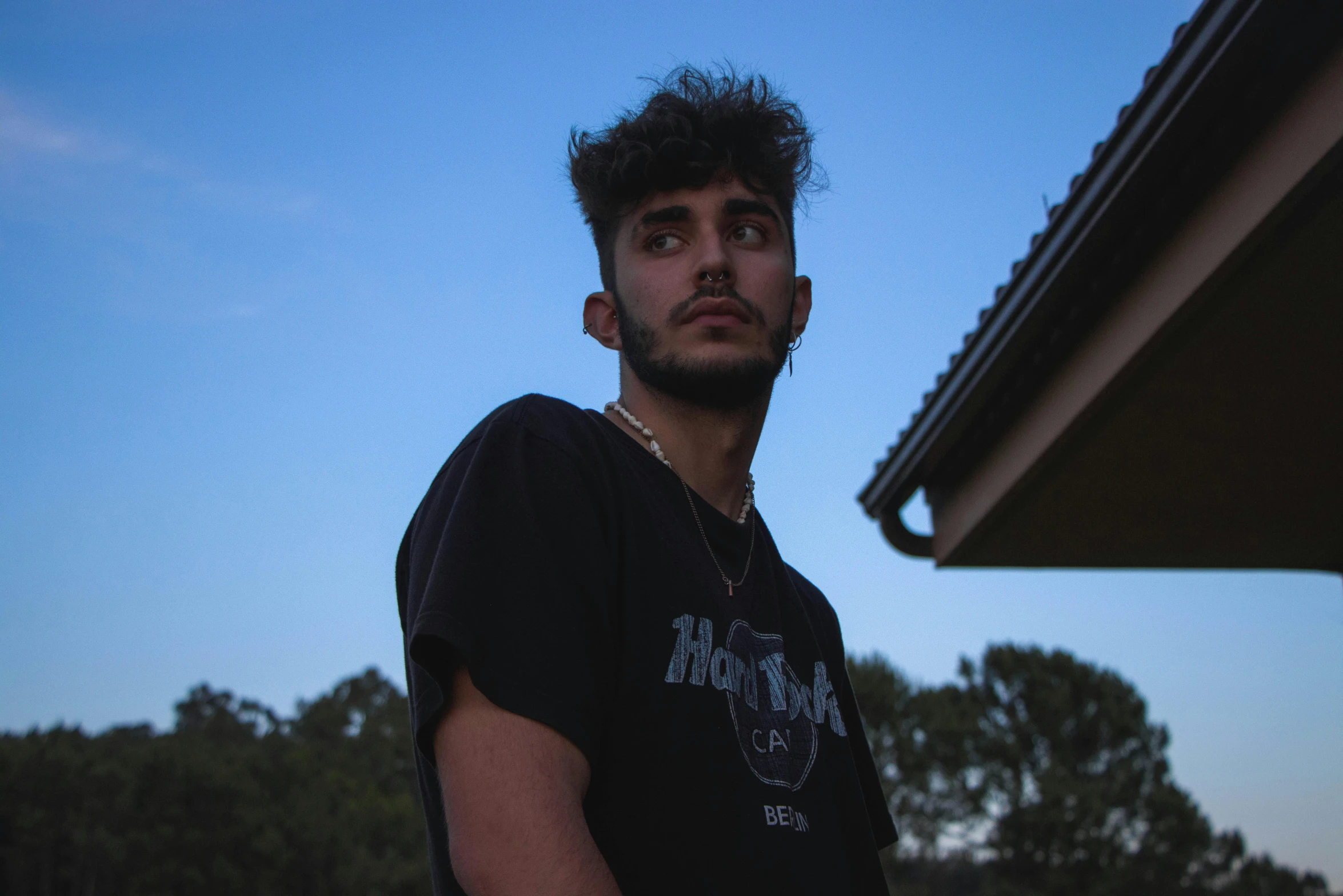 a man looking up into the sky while standing in front of some trees