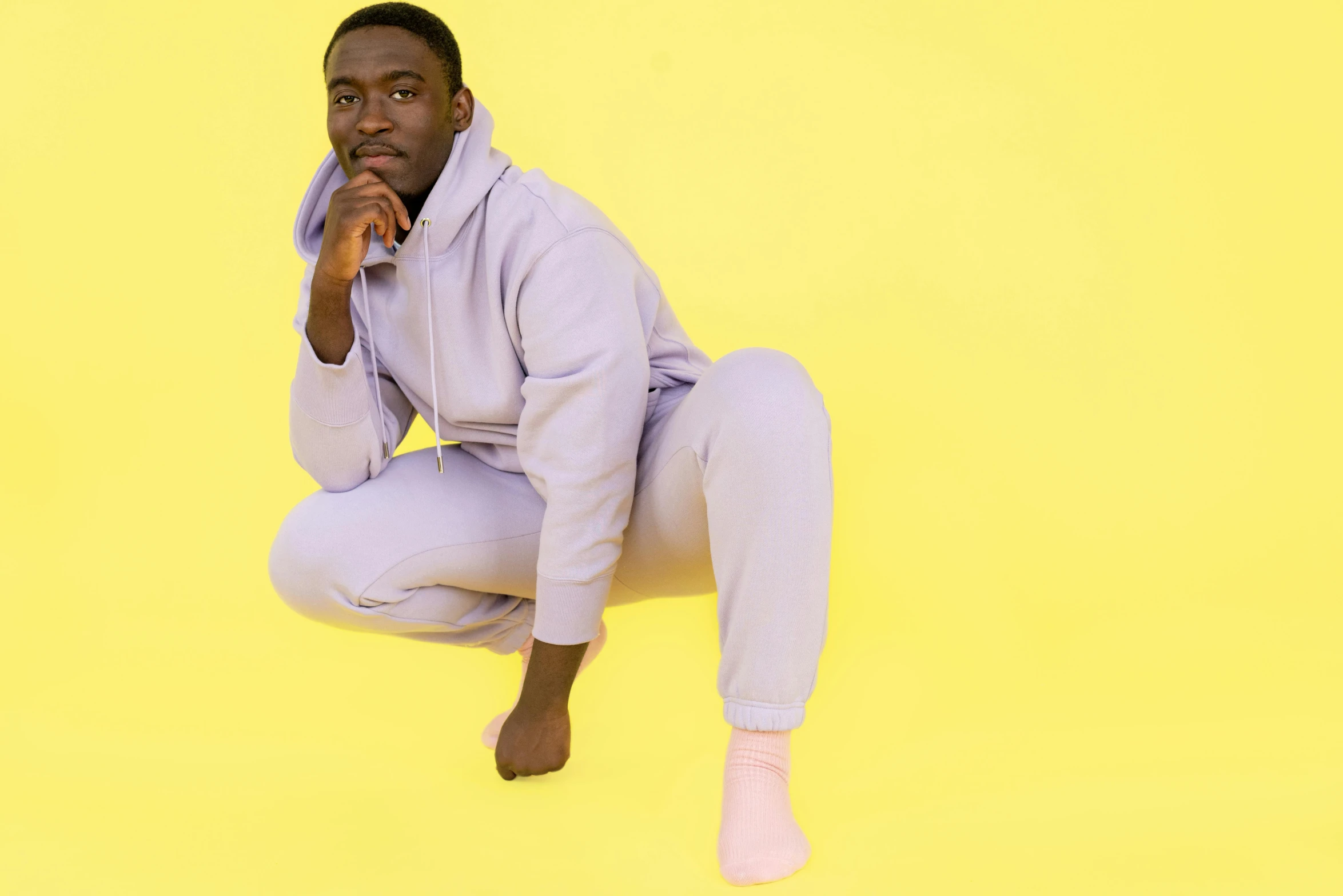 a black man sitting on the ground in pajamas and shoes