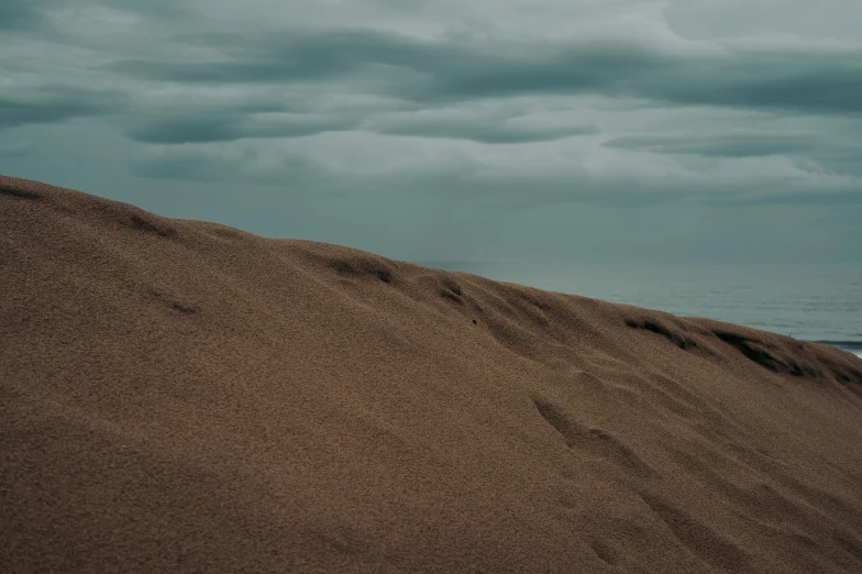 waves wash up on a sandy beach with dark clouds overhead