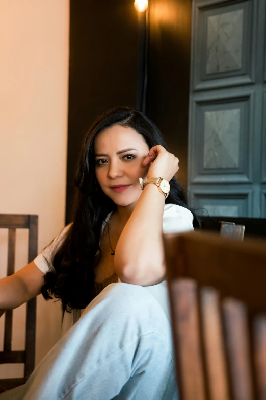 woman sitting on wooden chair in room with dark wall