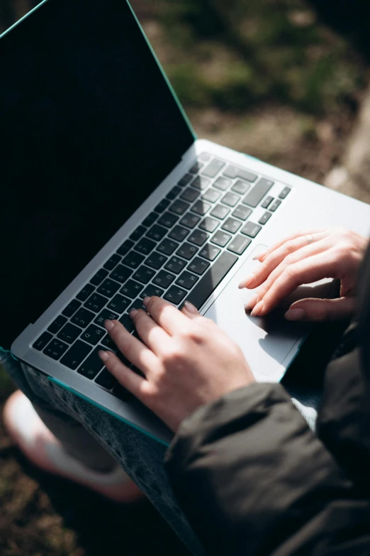 someone is typing on their laptop on a park bench